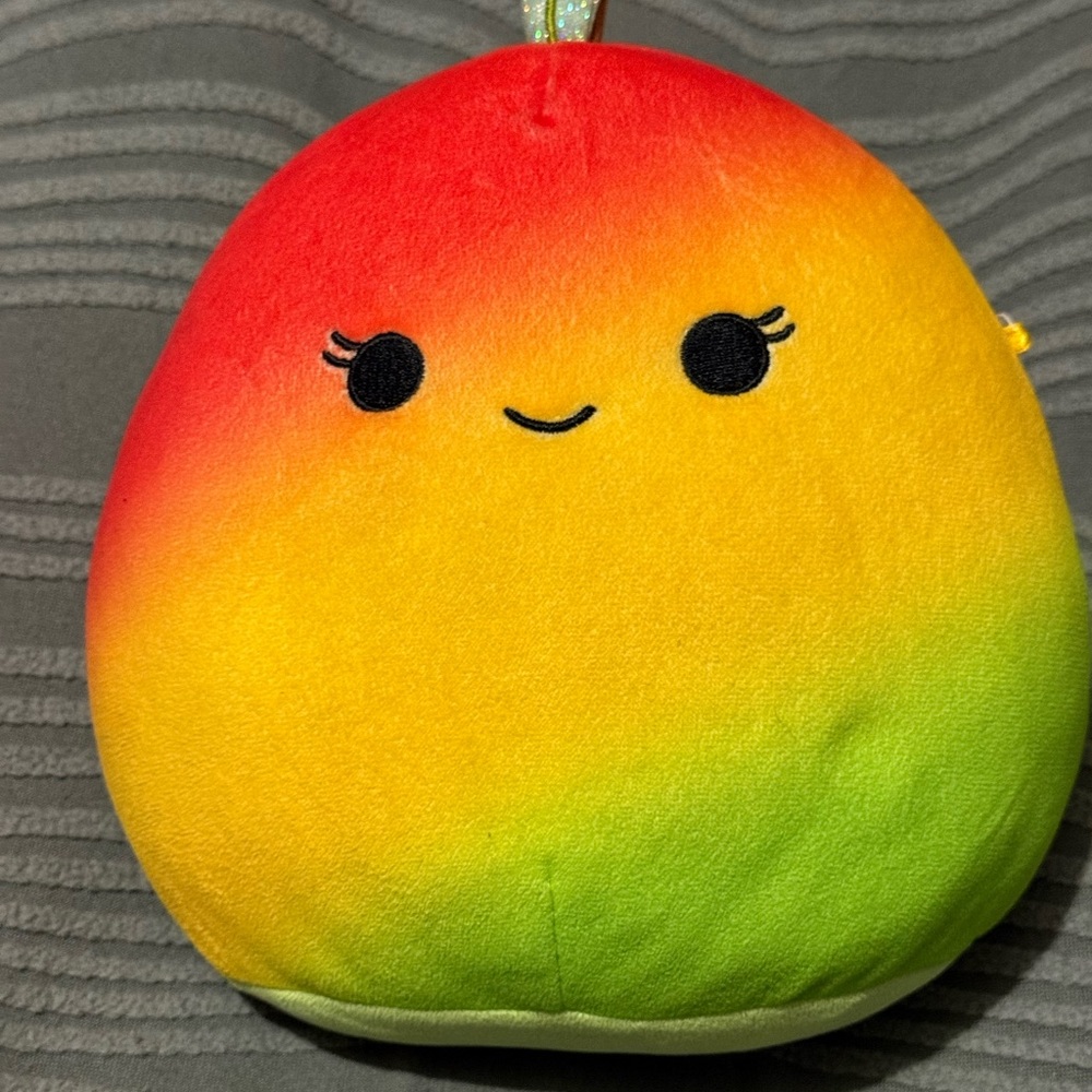 A collectible Squishmallows Ximena the Winking Mango Green and Yellow Plush